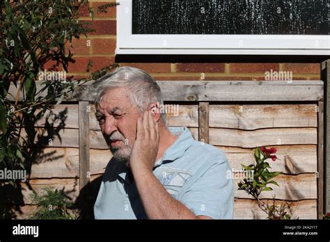 Elderly man with earache. In great pain and holding his ear. Ear ...