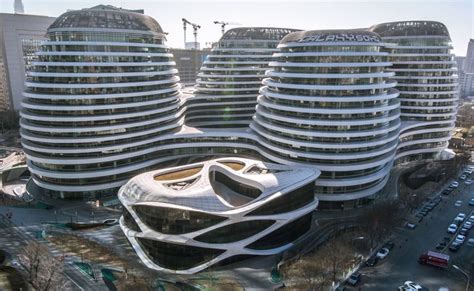 an aerial view of two buildings in the city with cars parked on the street below