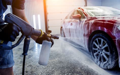 Premium Photo | Worker washing car with active foam on a car wash.