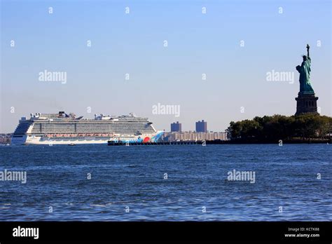 Norwegian Breakaway Cruise ship passing Liberty Island with Statue of Liberty beside in New York ...