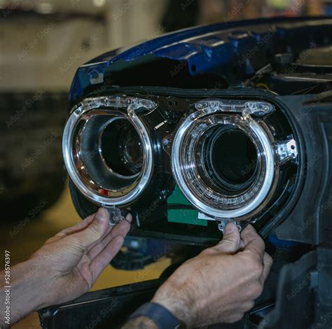 Car headlight in repair close-up. The car mechanic installs the lens in ...