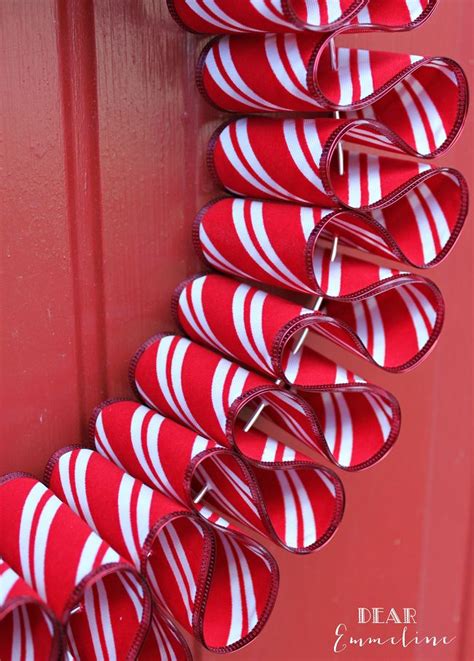 a red and white wreath hanging on the side of a door with ribbons ...