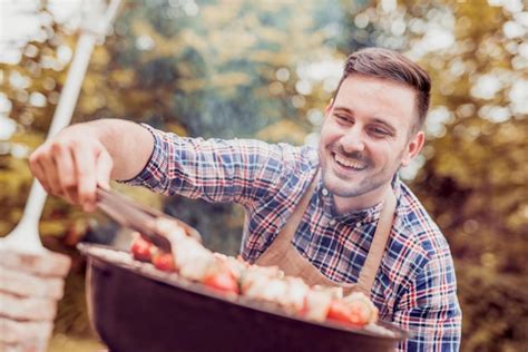 Premium Photo | Handsome happy male preparing barbecue outdoors