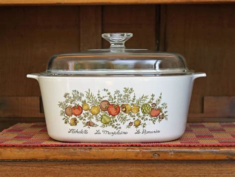 a white casserole dish on a red and yellow checkered place mat with an old fashioned glass lid