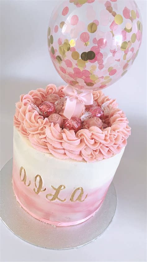 A beautiful blush pink buttercream cake with Lindor chocolate and a confetti filled balloon to ...