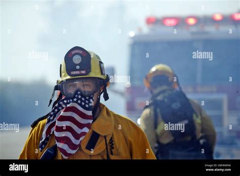 A firefighter covers his face with a U.S. flag scarf as he fights the ...