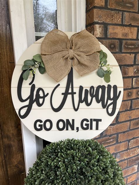 a sign that says go away go on, git next to a potted plant