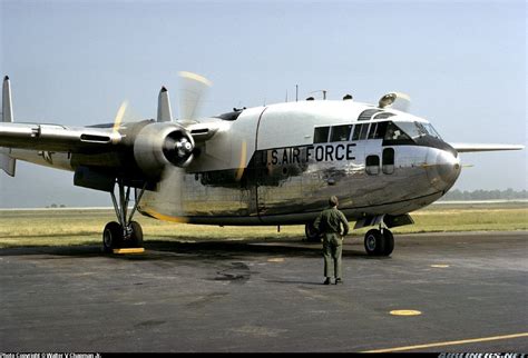 an air force plane sitting on top of an airport tarmac with two men standing next to it