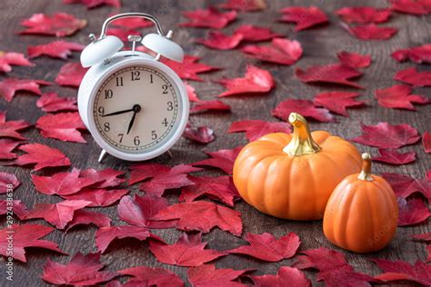 Fall color in red maple leaves on a rustic wood floor with ceramic pumpkins and a white analog ...