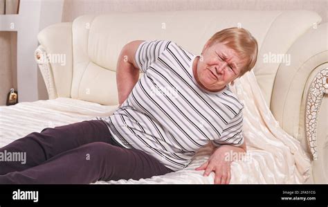 Elderly woman on bed with back pain Stock Photo - Alamy