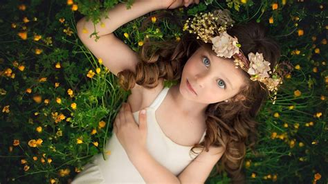 Cute Little Girl Is Lying On Yellow Flower Plant Looking Up Wearing Wreath And White Dress HD ...