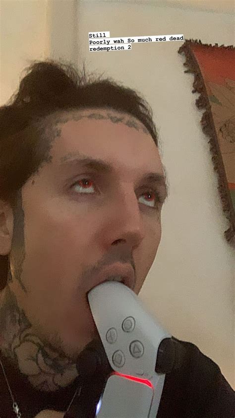 a man with tattoos holding a remote control in his mouth