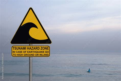 Tsunami warning and evacuation sign located on a beach. Blue calm sea ...