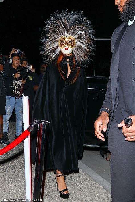 Doja Cat dons a Venetian mask with a feathered mane and black cape at ...