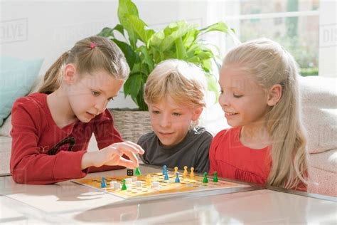 Three children playing a board game - Stock Photo - Dissolve