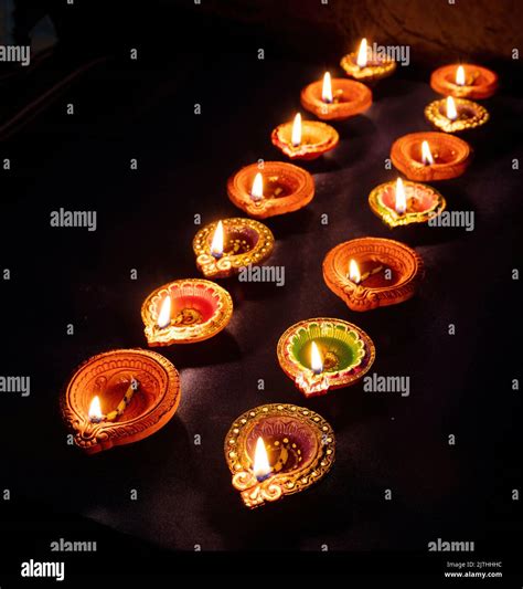 Diwali. Deepavali Hindu festival of lights. Clay diya candles in rows. Oil lamp lit on dark ...