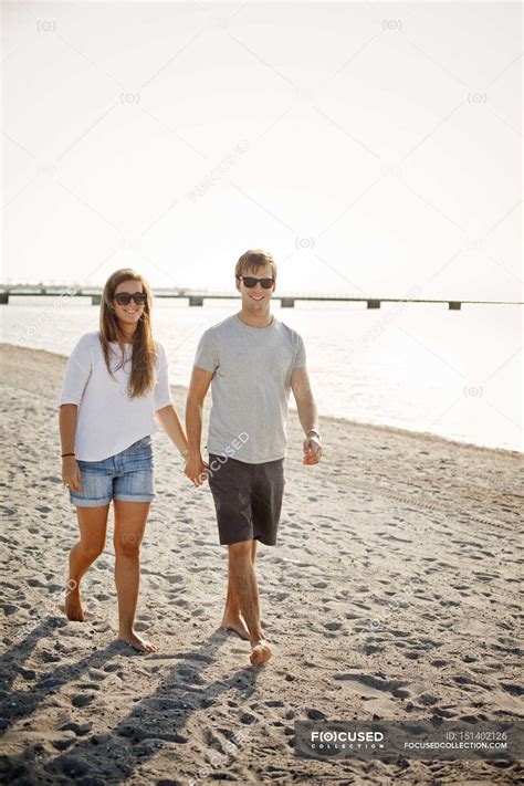 Couple holding hands while walking on shore — young, Beach Holiday ...