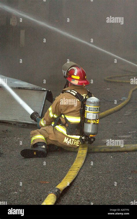 Fireman spraying water on a commercial warehouse fire filled with ...