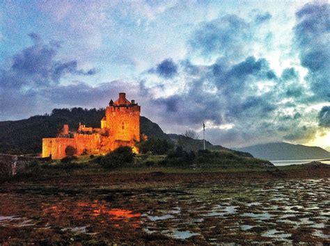 a castle sitting on top of a lush green hillside next to the ocean ...