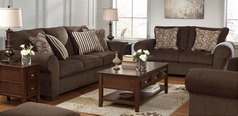 a living room filled with brown furniture and pillows