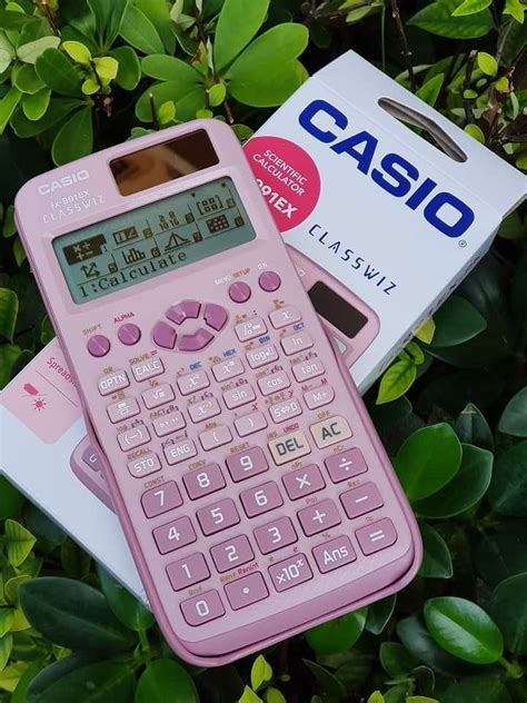 a pink calculator sitting on top of a box next to some green leaves