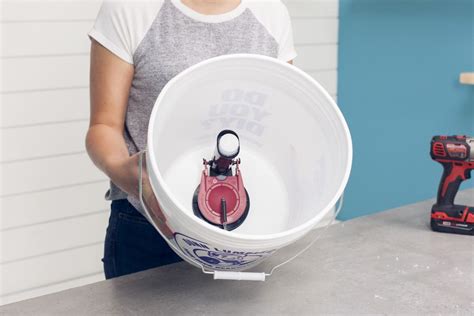 a woman holding a bucket with tools in it