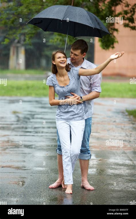 A young couple walking in the rain barefoot Stock Photo - Alamy