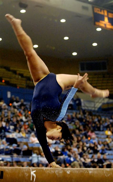 college gymnast with one hand on the balance beam, collegiate ...