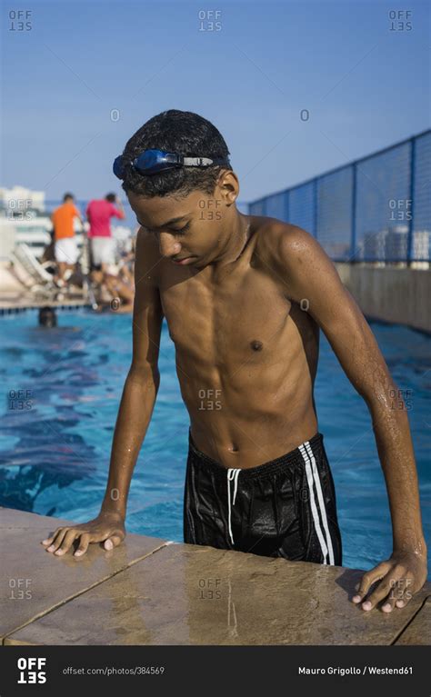 Teenage boy getting out of swimming pool stock photo - OFFSET