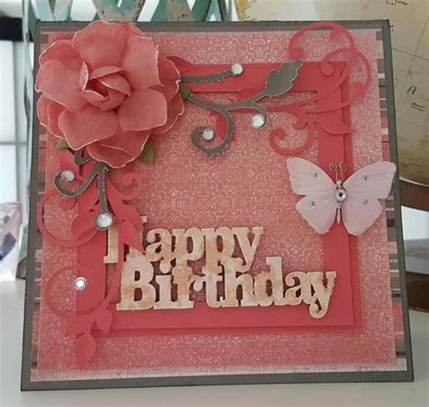 a birthday card with a pink rose and butterfly on the front, sitting on a table