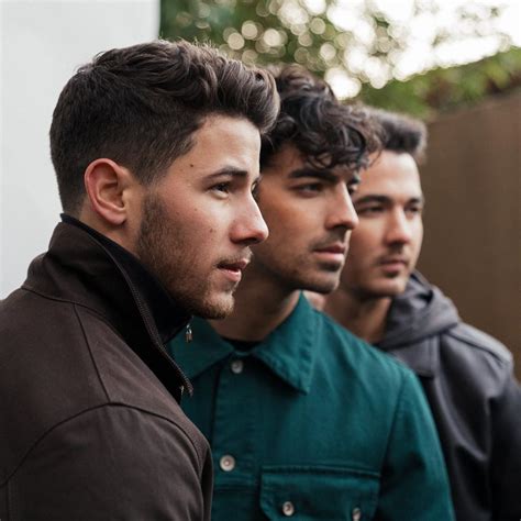 three men standing next to each other looking off into the distance