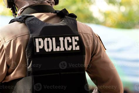 Back view of male police officer dressed. A bullet proof vest on his ...