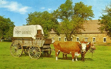 Ox-drawn covered wagon on parade ground at historic Fort Larned. Building in background is ...