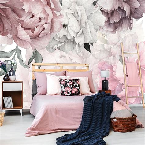 a bedroom with pink and white flowers on the wall, bed in front of it