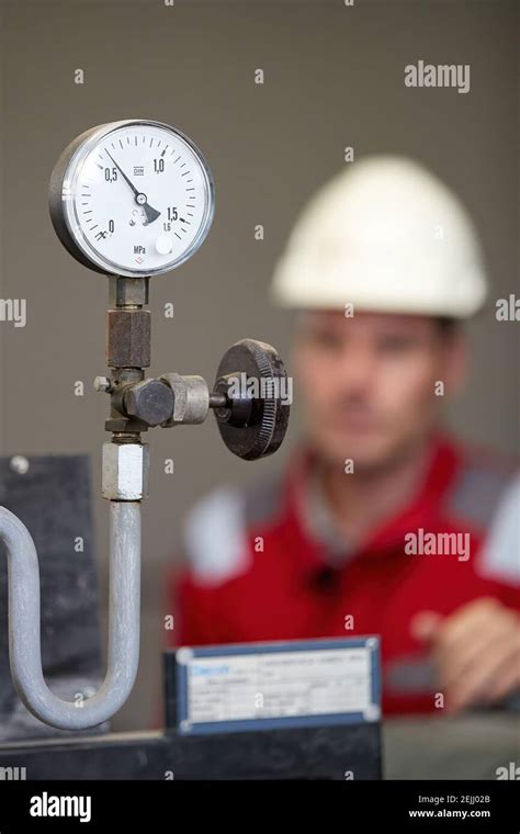 Thermometer on the hot water supply pipe, heating system. Technician wearing red jacket with ...