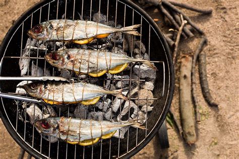 three fish are cooking on the grill with tongs