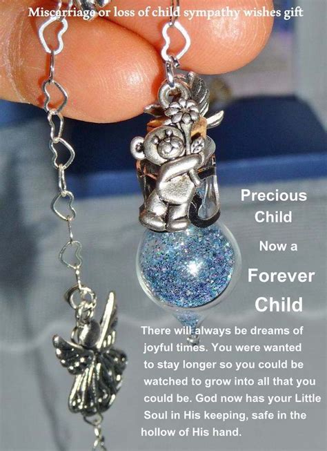 extreme closeup of Loss of Child Sympathy Tear vessel with a teddy bear and winged angel charms ...