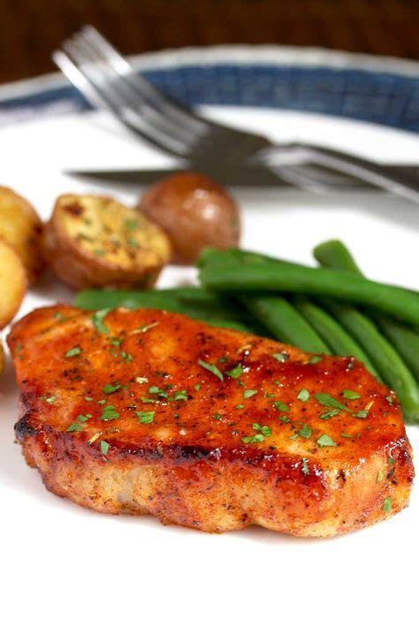 An oven baked pork chop on a white plate with roasted potatoes and green beans. | Boneless pork ...