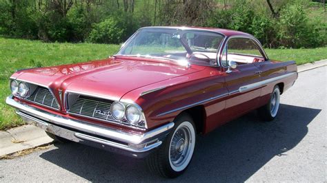 an old red car is parked on the side of the road