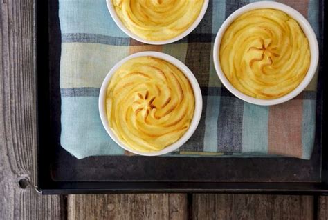 four small white bowls filled with food on top of a wooden table next ...