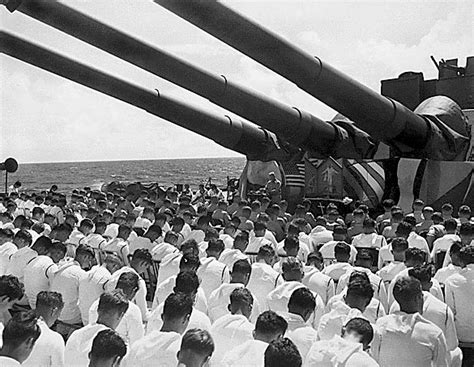 The crew of the USS SOUTH DAKOTA stands with bowed heads to honor killed shipmates