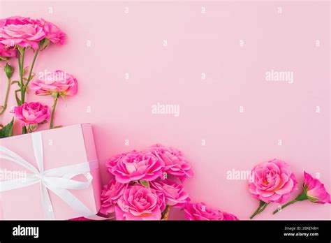 Floral frame of pink roses flowers and gift box on pink background. Flat lay, Top view. Happy ...