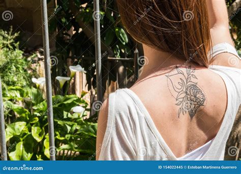 A Young Red-haired Tourist with an Arum-lily Tattoo on Her Back Looks at a Garden with the Same ...