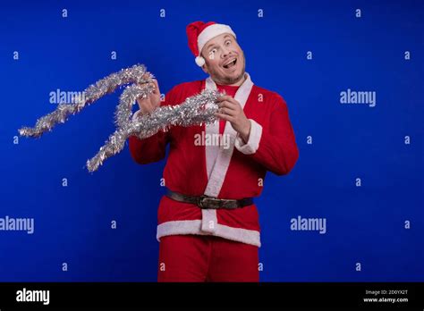 Male actor in a suit and hat of Santa Claus with a silver tinsel ...