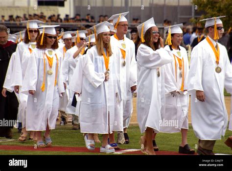 Wearing their distinctive white caps and gowns, National Merit Scholarship members participate ...