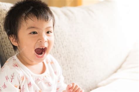 Premium Photo | Close up happy little girl smiling and laughing sitting on sofa.