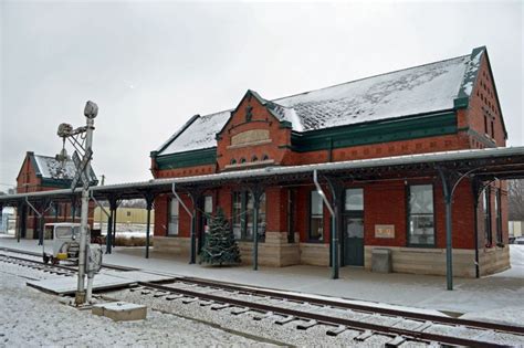 an old train station with snow on the ground and tracks in front of it,