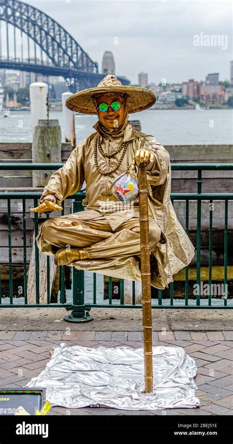 Gold live statue levitating street performance at Sydney Harbour Stock Photo - Alamy