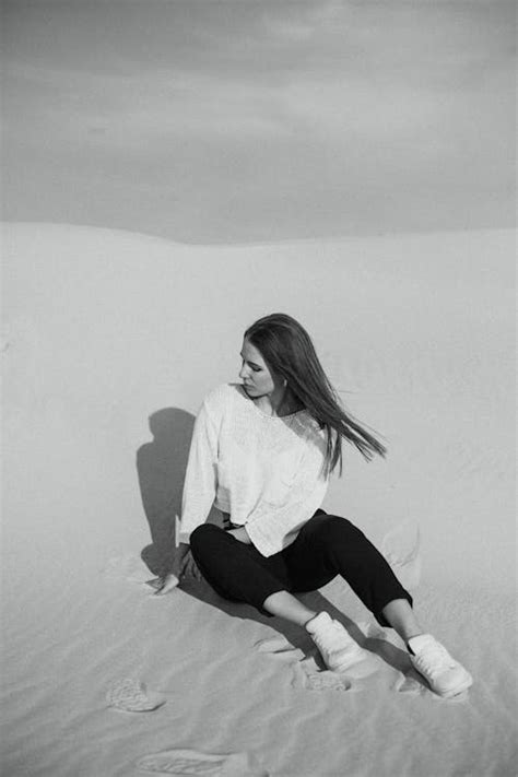 Grayscale Photography of Woman Sitting on Sand · Free Stock Photo