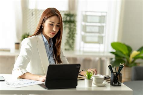 Beautiful young Asian girl working at a office space with a laptop ...